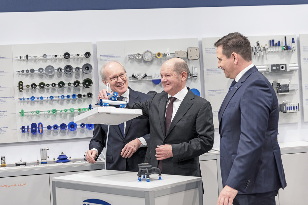 在施迈茨展厅，联邦总理（中）向施迈茨董事总经理库尔特-施迈茨博士（左）和 Andreas Beutel 了解真空技术。
